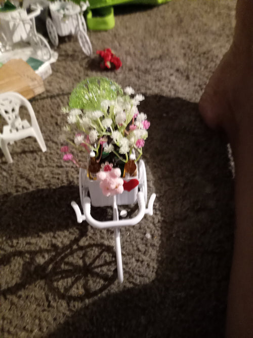 White decorative bicycle planter with white and pink wildflowers and red heart accent